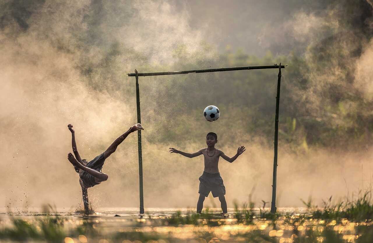 Beliebte Sportarten in Thailand, Zwei Jungen spielen Fussball in einem schlammigen Feld