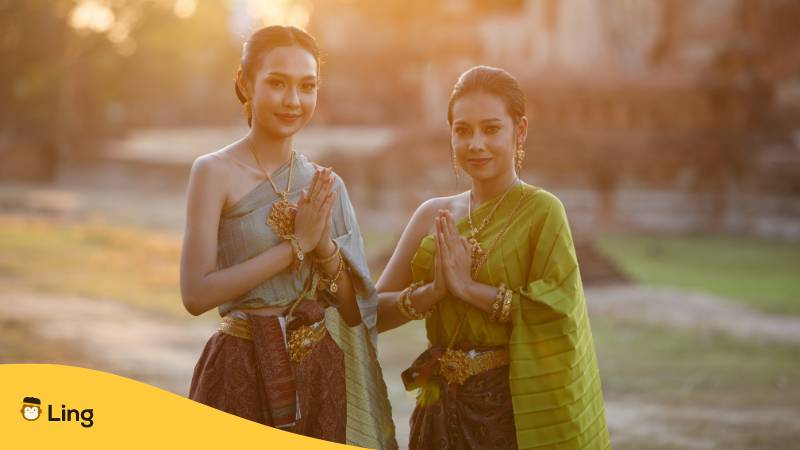 Thailändische Frauen in traditioneller Kleidung machen zur Wai-Gruß