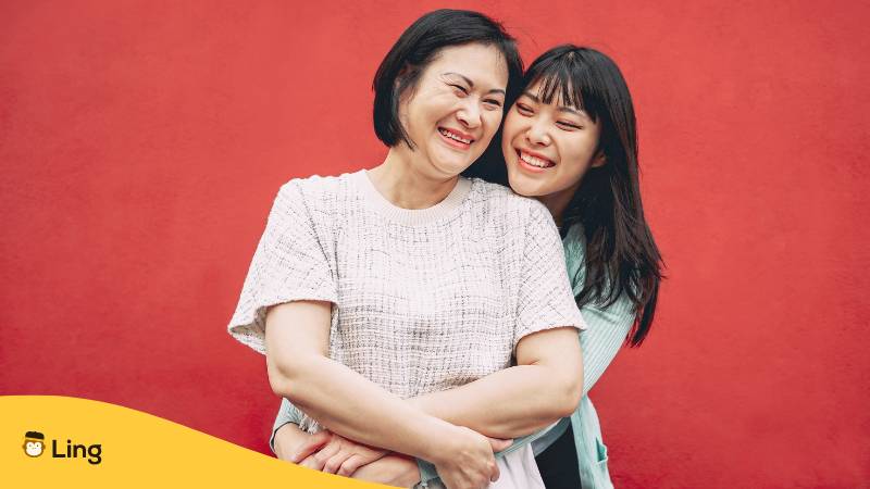 Tochter umarmt ihre Mutter dankbar von hinten in Thailand