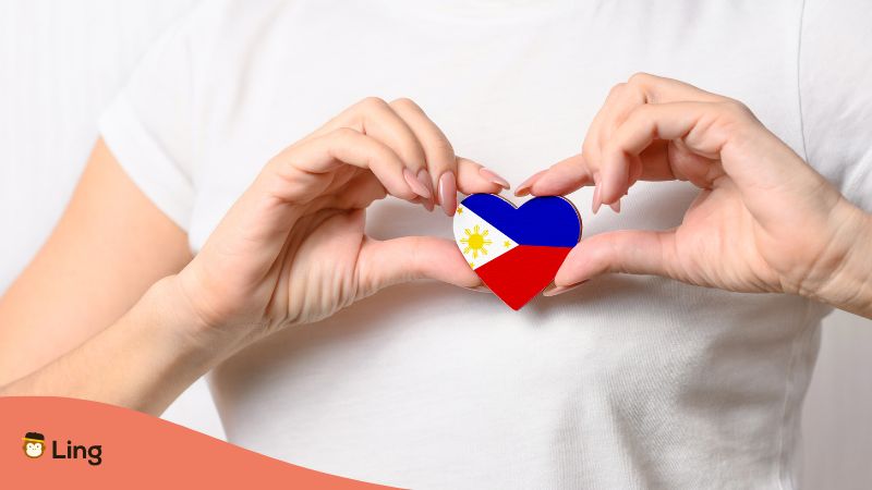 Hände die ein Herz formen und die philippinische Flagge in Herzform halten