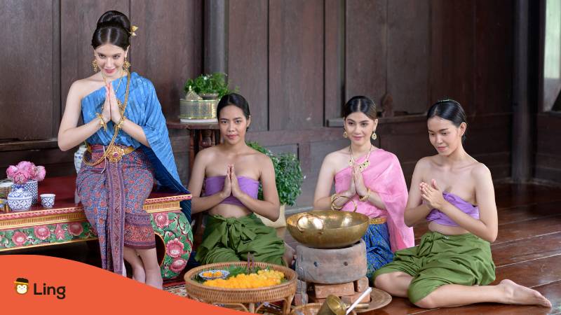 Thailändische Frauen in traditioneller Kleidung machen den thailändischen Wai als Zeichen der Höflichkeit in Thailand