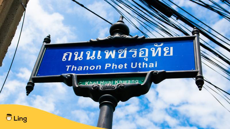 Thai Strassenzeichen mit Namen der Strasse in thailändischen Buchstaben und auch mit lateinischen Buchstaben