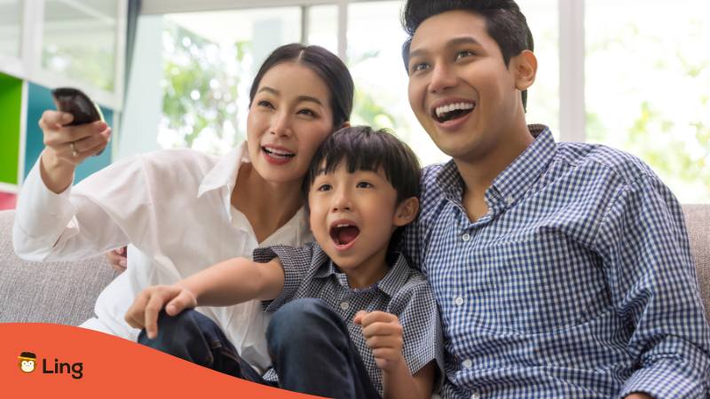 Eltern schauen Fernsehen mit ihrem Sohn, der einen thailändischen Spitznamen hat, der ihm Glück und Wohlstand bringen soll