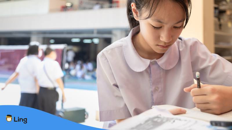 Thai Schülerin in Schuluniform lernt das thailändische Alphabet lernt