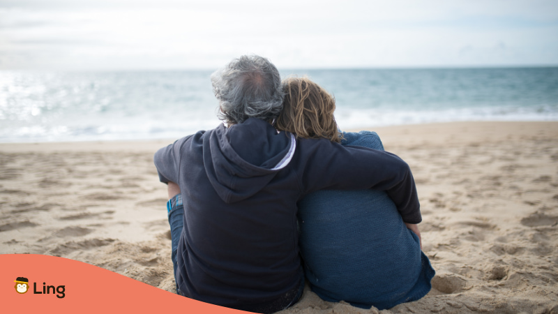 Older couple sitting and cuddling at a beach which is called Cơm Chó / Cẩu Lương in Vietnamese Slang words