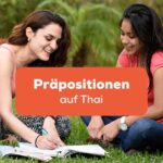 Zwei Frauen sitzen im Gras und lernen zusammen Präpositionen auf Thai mit der Ling-App