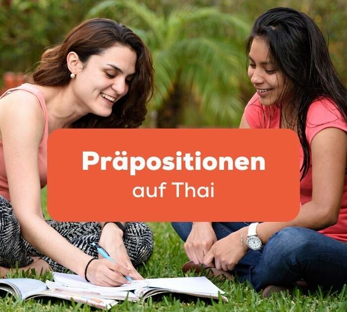 Zwei Frauen sitzen im Gras und lernen zusammen Präpositionen auf Thai mit der Ling-App