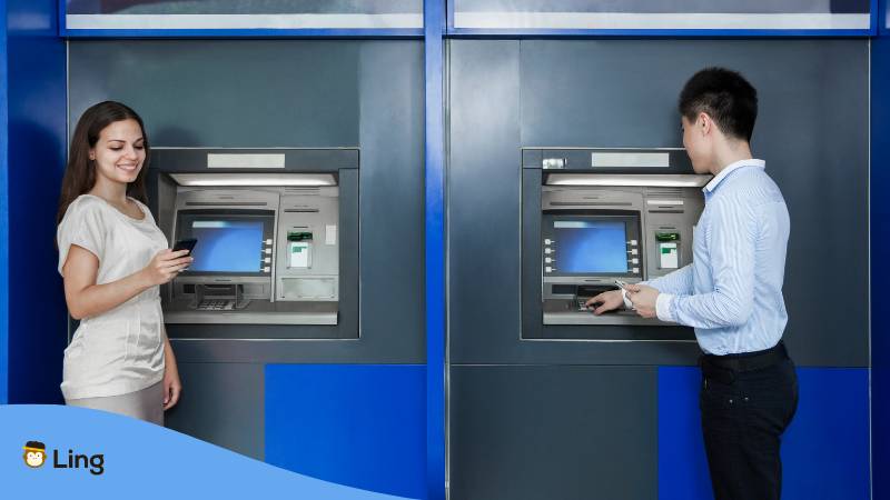 Blonde Frau und asiatischer Mann stehen am Bankautomaten in Korea und wollen Geld abheben