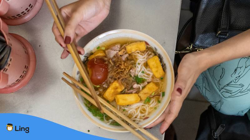 Table wit bowl of of tomato and Crab Noodle Soup Bun Rieu Cua