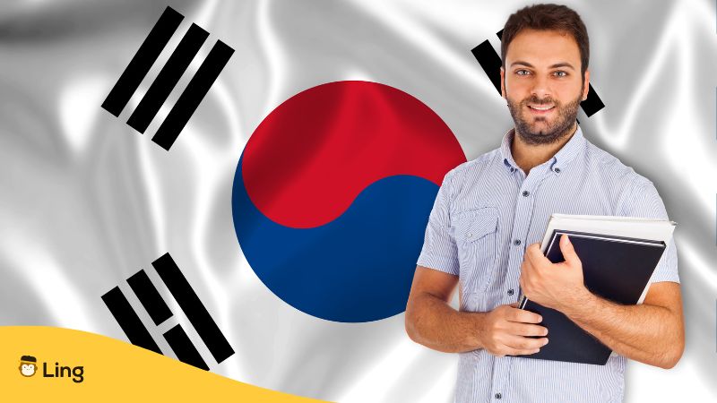 Mann mit Lernmaterialien in der Hand lernt Koreanisch vor einer grossen Flagge von Korea