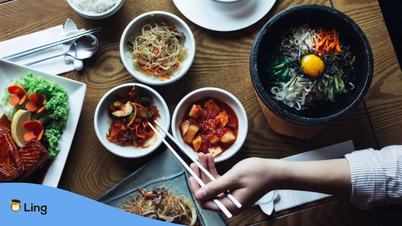 Tisch mit koreanischem Reisgericht Bibimpap und einigen Marinaden und Saucen