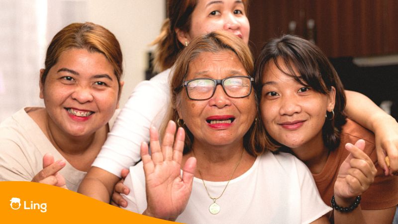 Group of four Filipino women smiling and gesturing a Hello in Tagalog into the camera