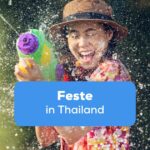 Frau mit Wasserpistole spritzt Wasser und feiert Songkran, eines der wichtigsten Feste in Thailand