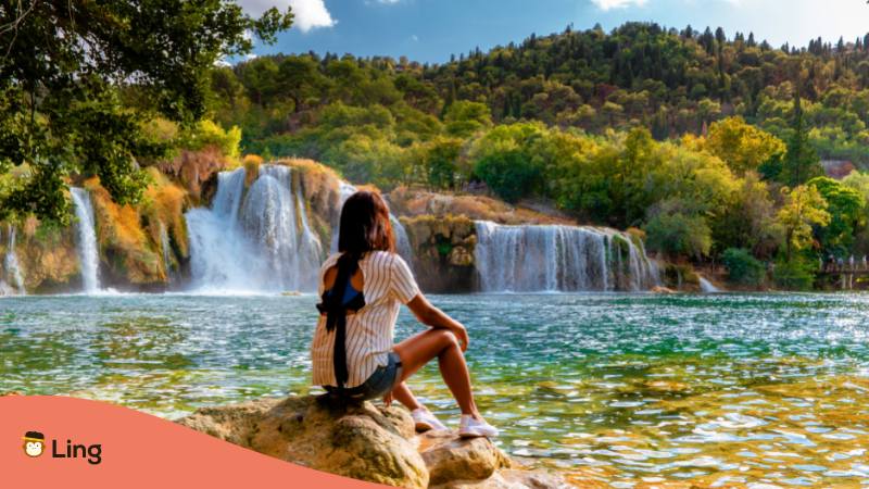 Frau sitzt auf einem Stein am Krk Wasserfall in Kroatien