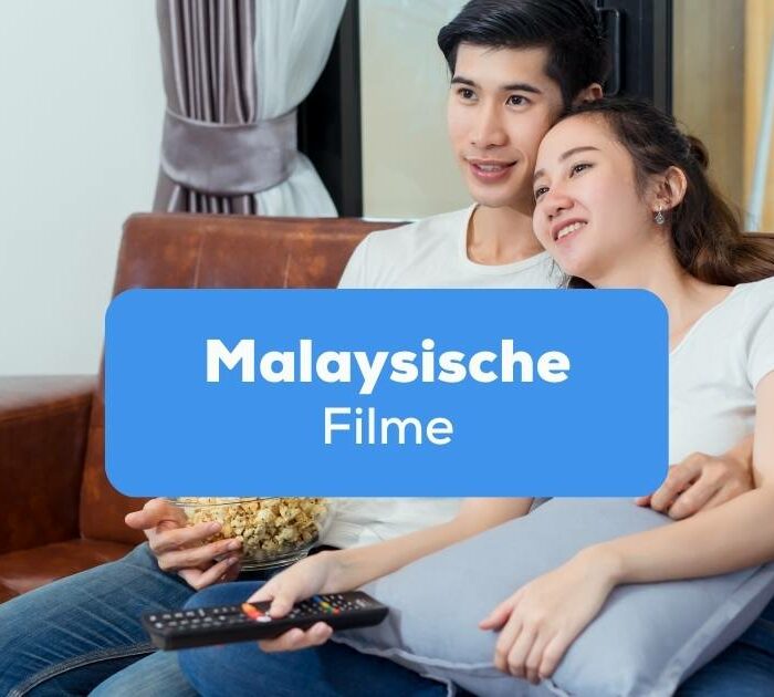 Paar sitzt auf dem Sofa und schaut gemeinsam malaysische Filme an