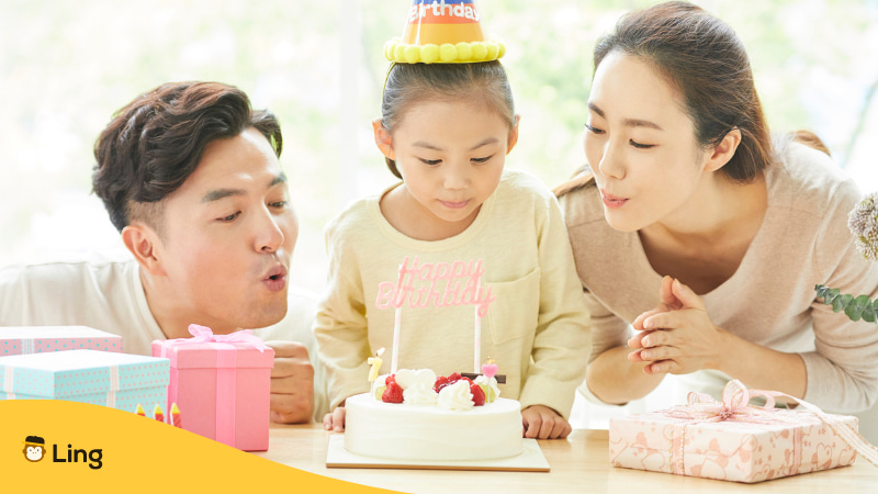 Japanese Father and Mother and doughter blowing out candles on a birthday cake
