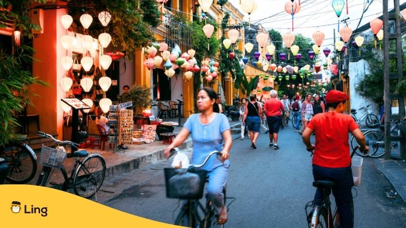 Strasse von Vietnam eine Frau auf einem Fahrrad fährt vorbei, ein Touristenpärchen schlendert vorbei