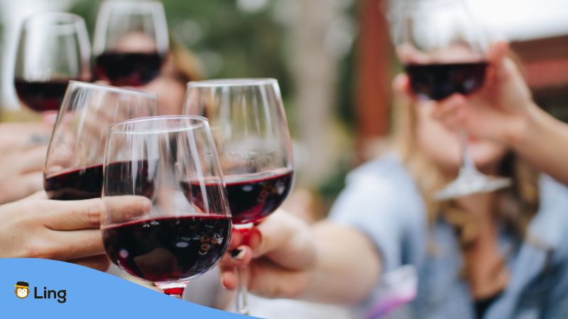 Menschen stoßen mit Rotweingläsern an, in denen kroatischer Wein drin ist