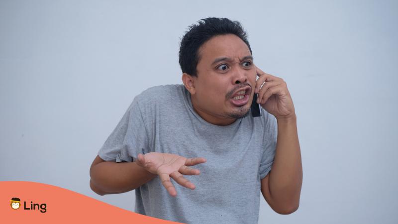 Filipino Mann ist am Handy und verärgert und sucht nach passenden Tagalog Schimpfwörter um sich auszudrücken