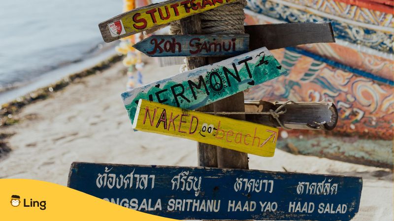 Wegweiser am Strand in Thailand, Richtungsangaben auf Thai