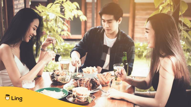 Drei Asiaten beim gemeinsamen Essen im laotischen Restaurant nachdem sie erfolreich Essen bestellt haben