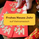 Hand hält rote Umschläge in der Hand um Frohes neues Jahr auf Vietnamesisch zu wünschen