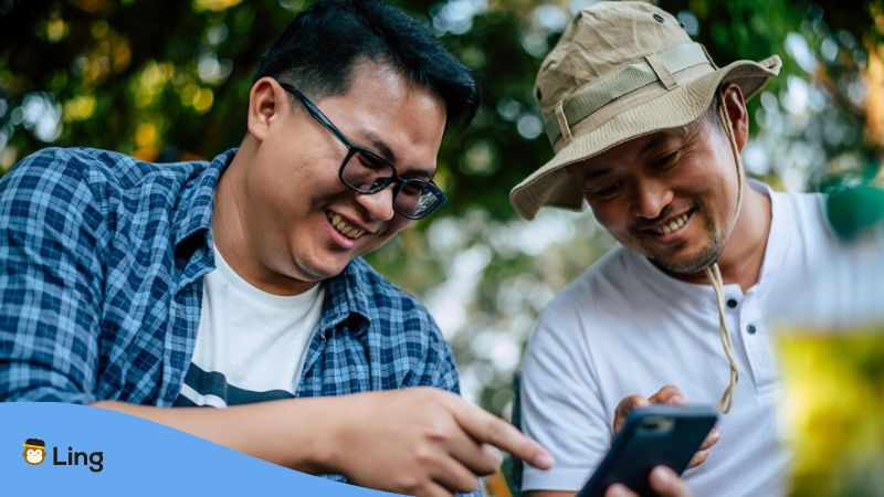 Tagalog Onomatopoeia - A photo of two men looking at a phone smiling.