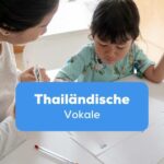 Mutter lernt mit Tochter thailändische Vokale an einem Schreibtisch