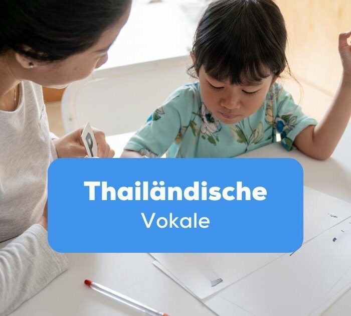 Mutter lernt mit Tochter thailändische Vokale an einem Schreibtisch
