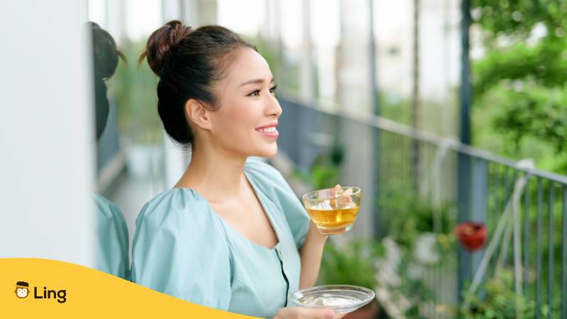 Vietnamesische Frau trinkt einen Tee auf einem Balkon und denkt über die vietnamesische Frauennamen nach
