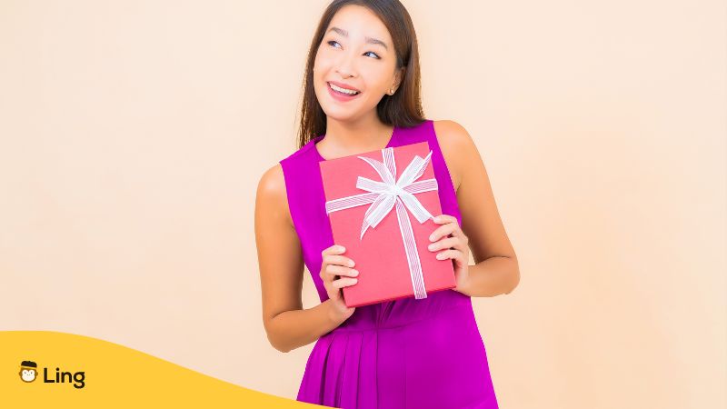 eine Japanerin freut sich über ein noch verpacktes Geburtstagsgeschenk, dass ihr auf einer Geburtstagsfeier übergeben wurde