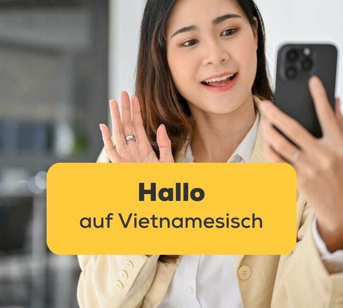 Vietnamesische Frau winkt in die Handykamera um Hallo auf Vietnamesisch zu sagen
