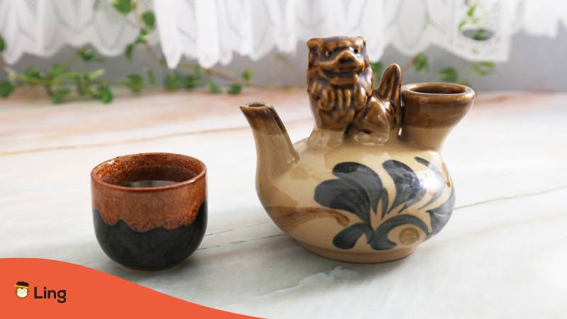 Brown teapot and teacup filled with distilled japanese alcohol Awamori