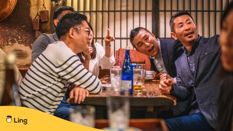 Befreundete Männer aus Japan sitzen an einem Tisch und trinken