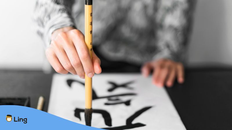 Eine Hand, die ein japanisches Schriftzeichen groß auf ein Papier schreibt