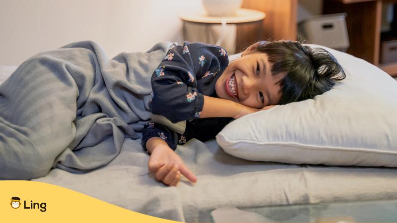 Philippinischer Junge liegt lächelnd im Pyjama im Bett