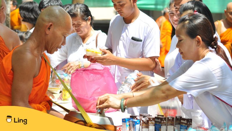 Menschen überreichen Almosen an den Buddhistischen Mönch im thailändischen Tempel