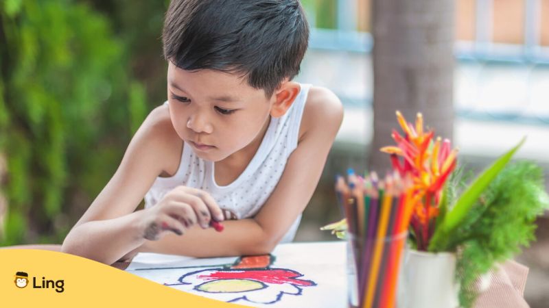 colors in Tagalog - A photo of a young Asian boy coloring a drawing book