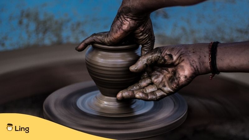 Malay Art. Close-up of a pottery wheel with hands creating a pot.