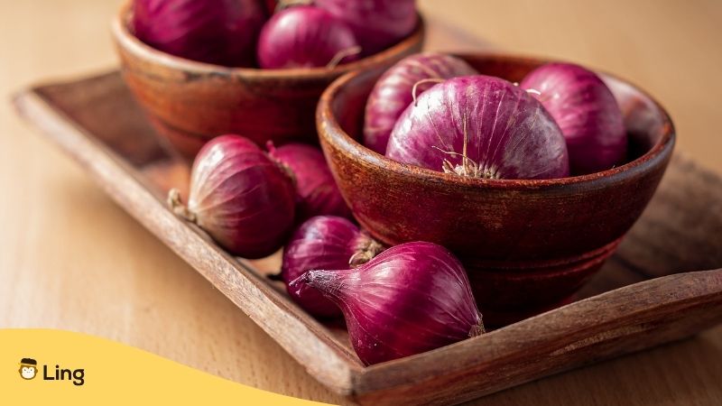 Plants In French. Red onions in brown bowls on a wooden tray.