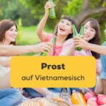 Fünf vietnamesische Freunde sitzen zusammen auf einer Picknickdecke und stoßen mit Bierflaschen gemeinsam and und sagen Prost auf Vietnamesisch