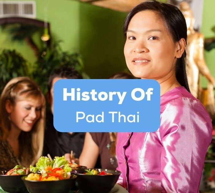 A Thai lady waitress who knows the history of Pad Thai serving tourists Thai foods.