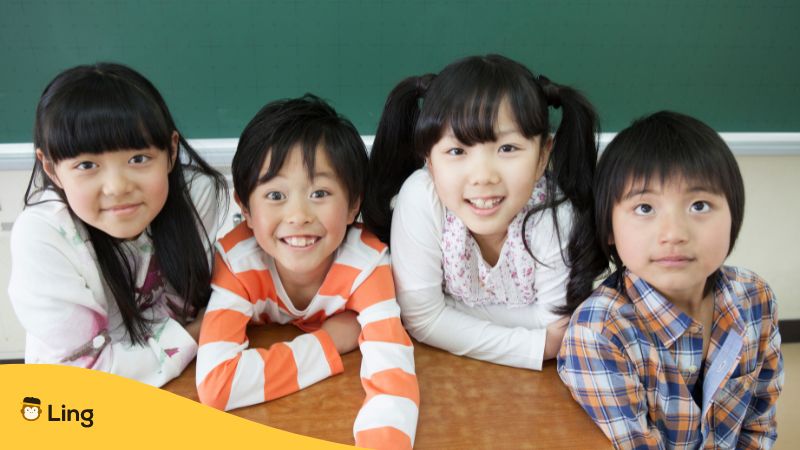 Zwei japanische Mädchen und zwei japanische Jungen lachen in die Kamera