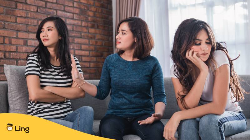 Drei vietnamesische Freundinnen sitzen auf einem Sofa und streiten sich und sagen auch vietnamesische Beleidigungen