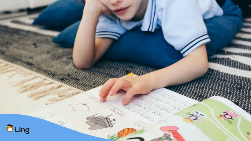 A photo crop of a boy reading Basic Malay Phonetics