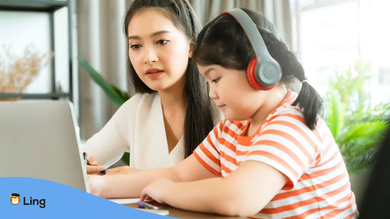 A photo of a mother and daughter learning the Cantonese language online in front of a laptop.