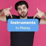 A man in black shirt pointing to instruments in Malay.