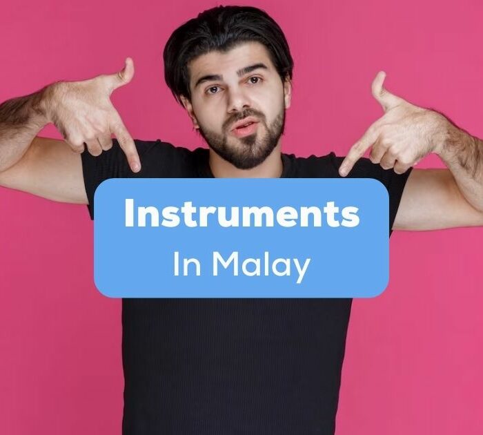 A man in black shirt pointing to instruments in Malay.