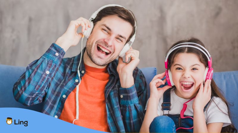 Father and daughter listening to Thai podcasts at home on the couch.