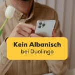 Mann hat Handy in der Hand und wundert sich warum es kein Albanisch bei Duolingo gibt, aber es gibt zwei wunderbare Alternativen